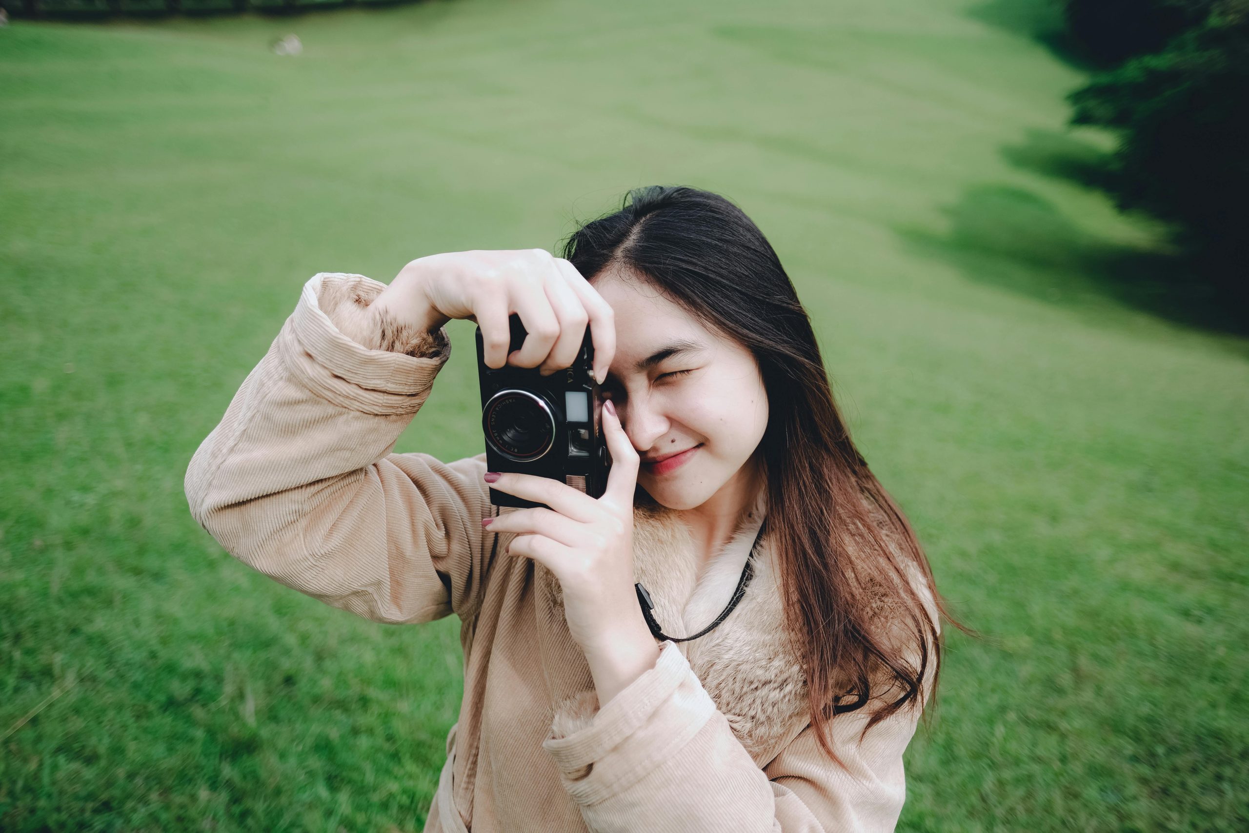 Smiling woman with long hair takes a photo outdoors in Indonesia. Vibrant green scenery.